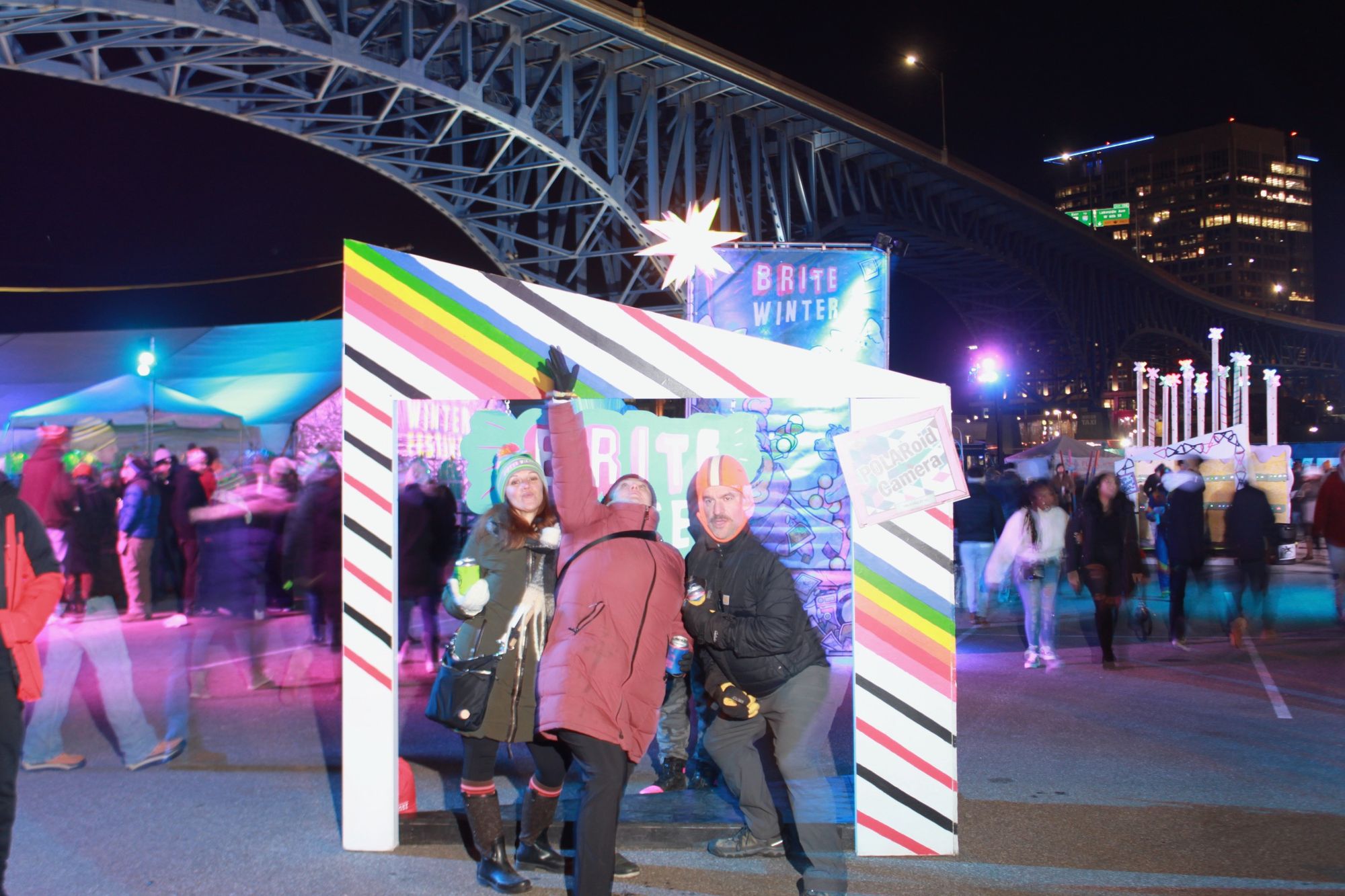 Festival attendees pose (from the camera's perspective) while ephemeral images of people, lights, and the city as backdrop.